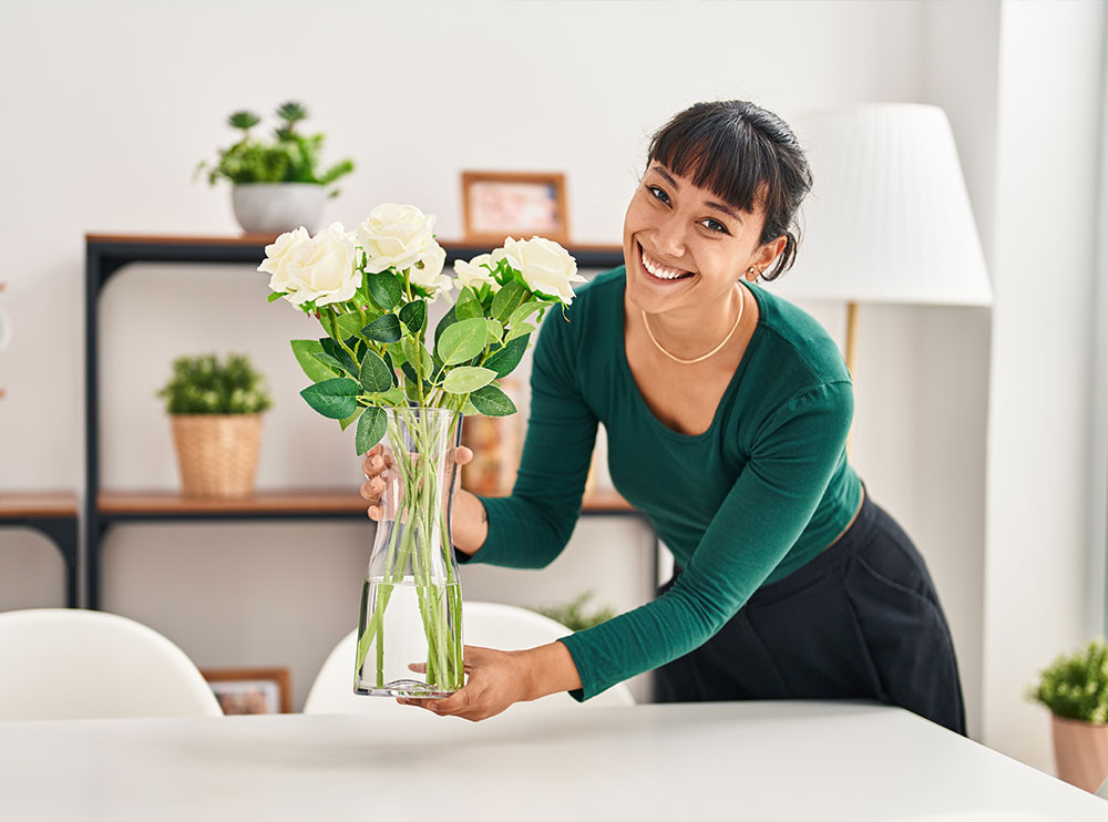 Frau platziert Blumen auf einem Esstisch